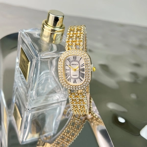 Detail of luxury gold oval watch with crystal encrusted bracelet and roman numerals dial