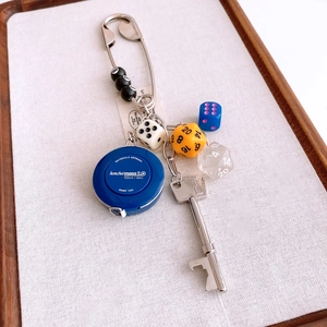 Macro detail of creative keychain featuring a 150cm measuring tape and colorful dice charms