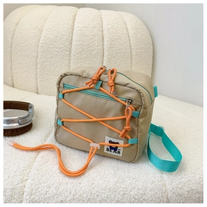 Detail of beige kids crossbody bag with orange drawstring and cartoon bear patch