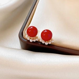 Dettaglio di orecchini placcati oro 18k con perline rosse, perle e accenti di zircone