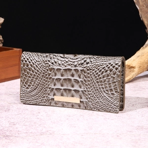 Detail of gray crocodile pattern leather wallet with minimalist gold metal decorative bar