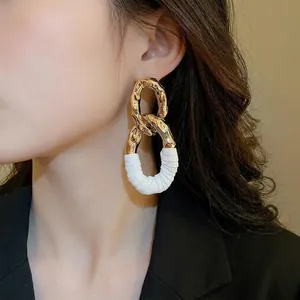 Boucles d'oreilles ovales torsadées en similicuir doré portées par un mannequin de profil