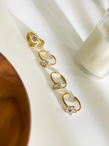 Gros plan de bagues en acier titane doré avec motifs de cœur, zircon carré et fleur