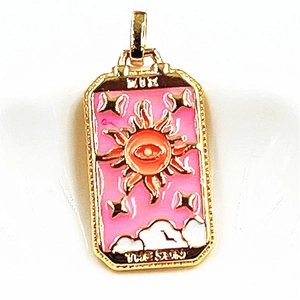 Macro shot of gold tarot sun pendant featuring pink enamel, orange sun and eye pattern