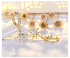 Detail of gold-plated star drop earrings with sparkling white zircon inlays and hoop