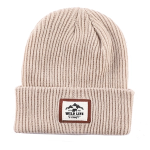 Detail der beige Strickmütze mit dem Outdoor-Abenteuer-Stickaufnäher und Rippmuster