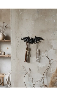 Detalle de un gancho de murciélago de hierro fundido vintage con llaves y joyas en la pared