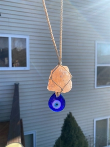 Detail view of pink crystal hanging ornament with Evil Eye charm and hemp rope