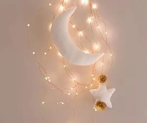 Detail of soft white moon and star felt ornaments with warm copper wire LED fairy lights