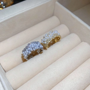 Macro view of gold and silver open rings with pavé crystals and clusters of white pearls