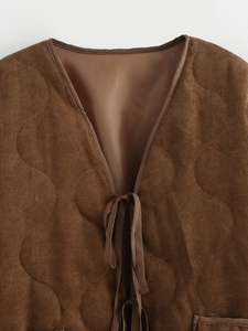 Detail van een bruin corduroy vest met golvende stiksels en een handige striksluiting