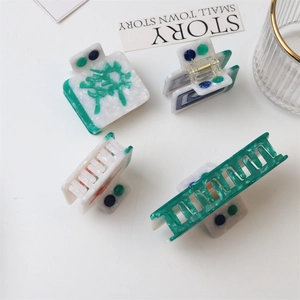 Detail of four green and white mahjong style hair claws with resin marble texture