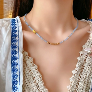 Gros plan détaillé d'un collier de perles bleu clair avec touches dorées sur un modèle