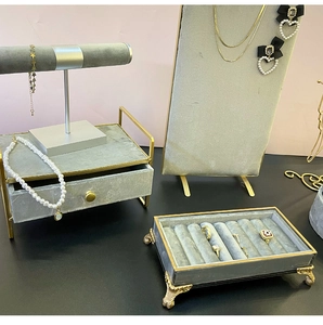 Detailed set of grey velvet and gold metal jewelry displays for rings and necklaces