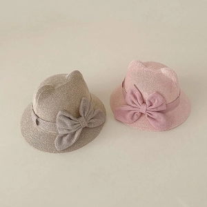 Detail of woven baby sun hats with cute cat ears and large decorative bows in beige and pink