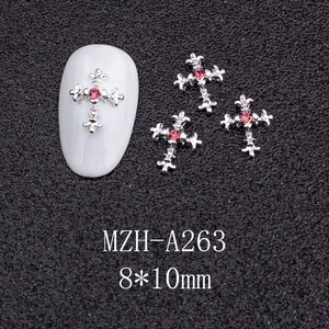 Macro detail of silver cross nail charm with pink rhinestone for DIY manicure art