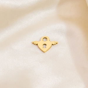 Golden heart wing pendant with keyhole detail on elegant beige silk fabric background