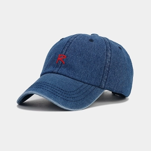Close-up of red embroidered R letter on blue denim baseball cap with distressed brim