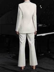 Elegant white slim-fit women suit with cutout blazer and flared trousers on piano stage