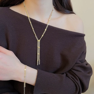Macro shot of layered gold fringe necklace and matching bracelet set on model