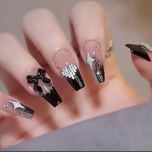 Detail of long coffin nails featuring black and clear mix with bow and rhinestone accents