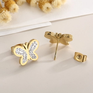 Detail of gold butterfly stud earrings featuring white pave-set stones and smooth metal back