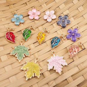 Detail of DIY enamel floral and maple leaf pendants for jewelry making on bamboo mat