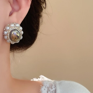 Macro detail of vintage baroque stud earrings with grey faux pearl and sparkling crystals