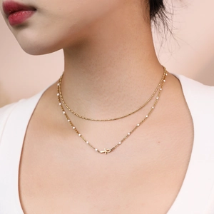 Detail of layered gold Ankh necklace with white beads on model in bohemian style