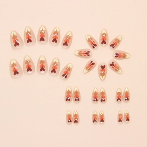 Almond-shaped press-on nails set with warm gradient heart patterns in ginger and brown