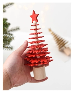 Handheld view of a mini wooden Christmas tree with red snowflake layers and a star