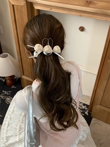 Détail de la pince à cheveux rose en soie crème avec rubans élégants sur un mannequin