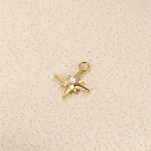 Detailed view of an eight-pointed star charm in gold with a central white zircon stone