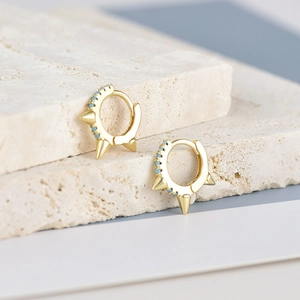 Punk style gold spike hoop earrings with blue turquoise stones on a stone base
