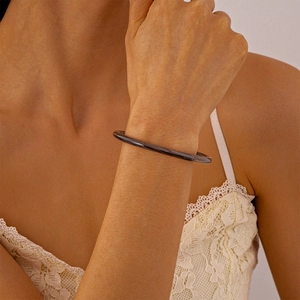 Détail d'un bracelet jonc en acrylique translucide foncé avec une finition brillante