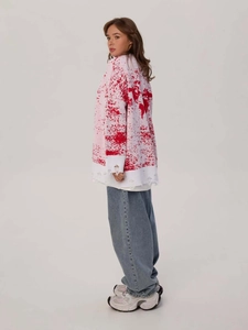 Oversize white knit sweater with red splash print and distressed ripped hem detail