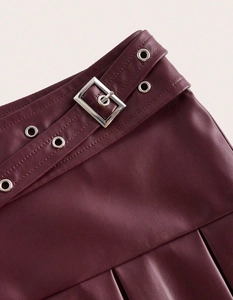 Détail d'une jupe plissée en similicuir bordeaux avec ceinture à boucle en métal argenté