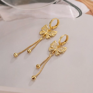 Macro detail of 18K gold butterfly earrings with zircon inlay and hanging tassel chains