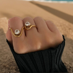 Detail of 18K gold rings with round and pear-cut zircon stones on a wavy band