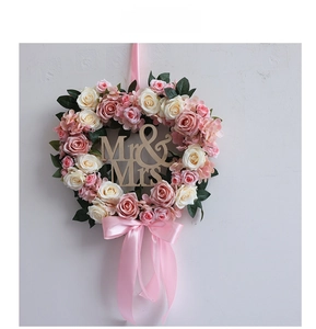 Detail of heart-shaped faux rose wreath with Mr & Mrs sign and pink ribbon for weddings