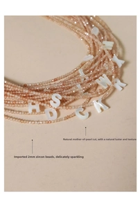 Detailed close-up of 2mm zircon beads and a natural shell letter pendant necklace