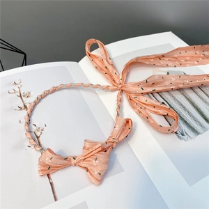 Detailed view of a pink floral bow headband with long ribbons on an open book