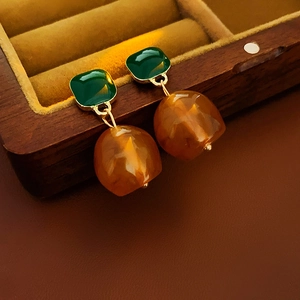 Detailed shot of retro geometric resin earrings with amber drop on a velvet jewelry box