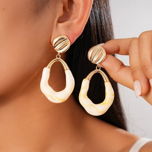 Chic gold-tone drop earrings featuring marble resin oval hoops on a female model