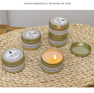 Close-up of lit natural soy wax candle in gold tin with smokeless cotton wick and flame