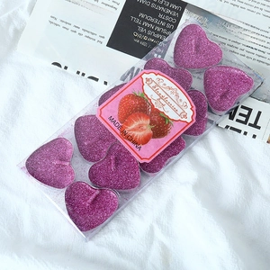 Close-up of heart-shaped strawberry scented tealights with glitter in clear box