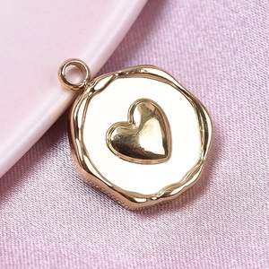 Macro detail of a golden heart pendant with hammer texture finish on silk fabric