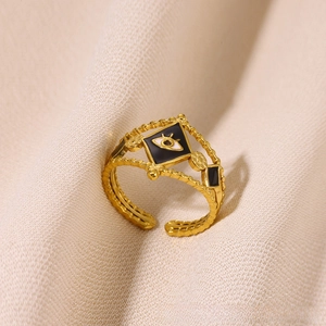Close-up of gold evil eye ring with black diamond inlay and beaded band texture