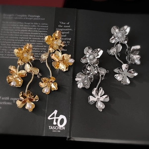 Boucles d'oreilles fleurs métalliques avec perles dorées et argentées sur un livre