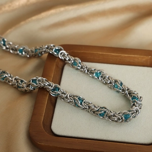 Chunky titanium steel chain necklace with blue crystal beads on a wooden display tray